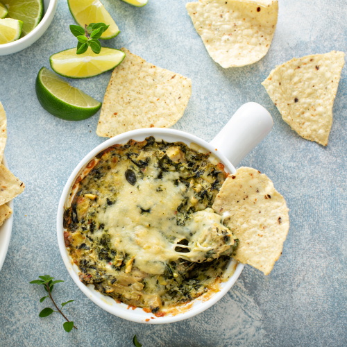 Artichoke spinach dip in a baking dish with a cheese pull